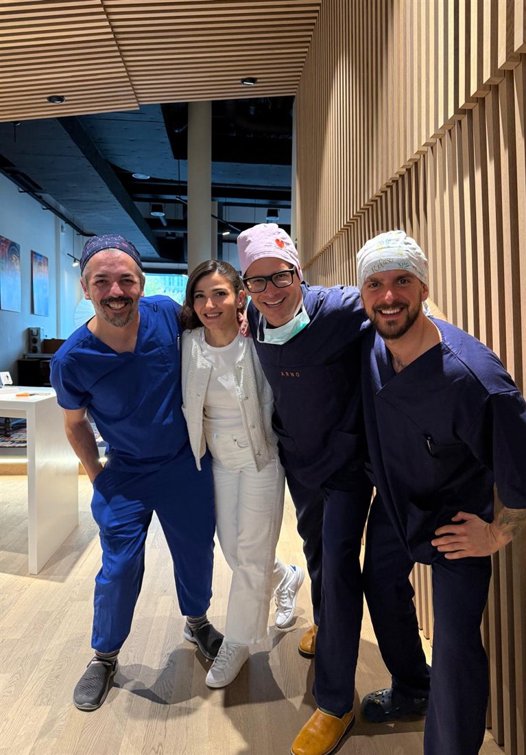 Das lächelnde Team von My Laser Vision Arm in Arm im Praxisgang mit Holzlamellen